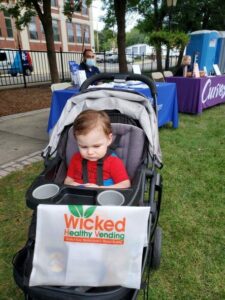 Picture of a young child in a stroller with a Wicked Healthy branded bag